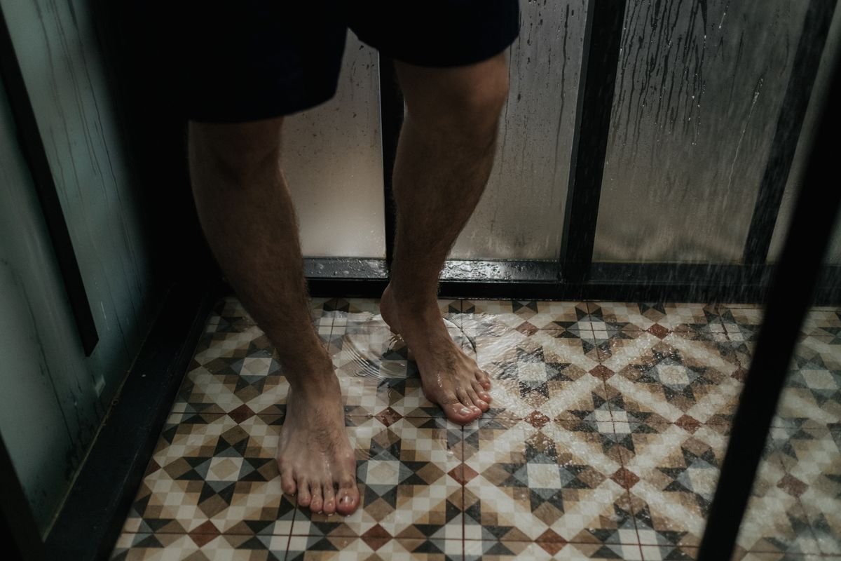 Bare feet on a wet tiled shower floor — where athlete's foot is caught and passed on