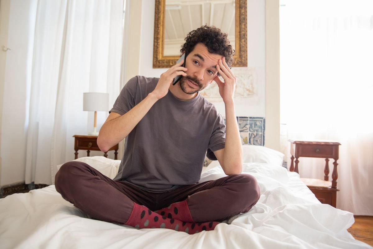 Man sitting on his bed making a private phone call