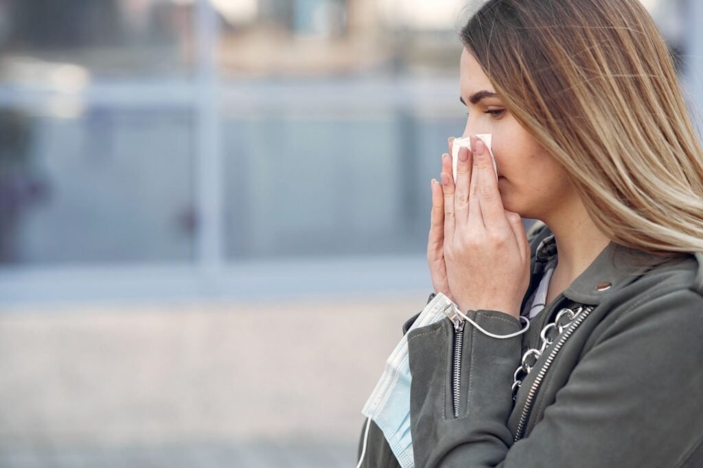 Person with hay fever sneezing outdoors while holding a tissue