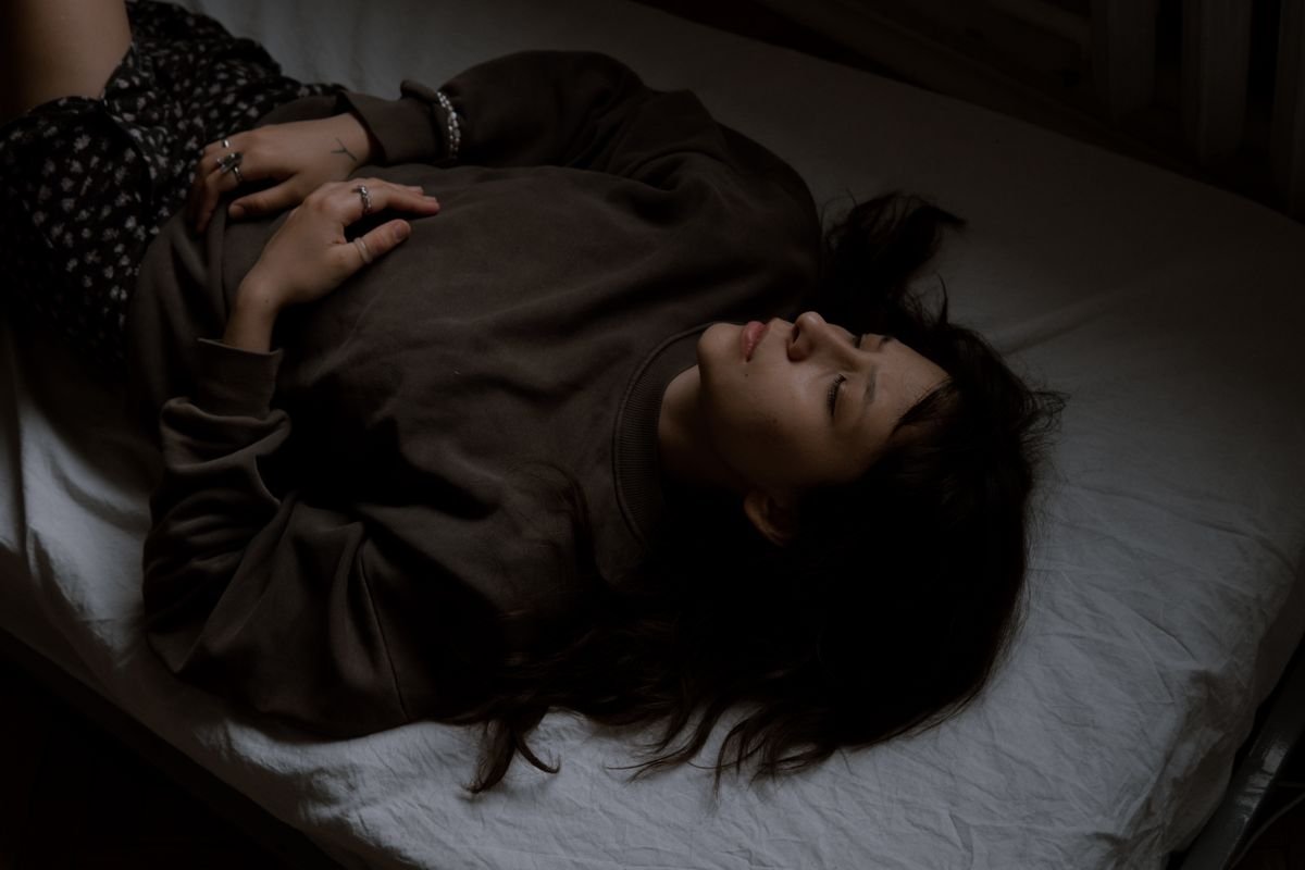 Woman resting with closed eyes in a dimly lit room during a migraine